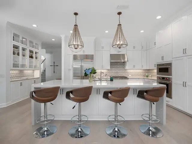 White shaker kitchen in Jacksonville with a quartz island, stainless appliances and woven pendant lights